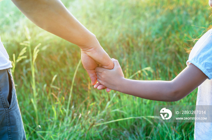 a parent holds the hand of a small child