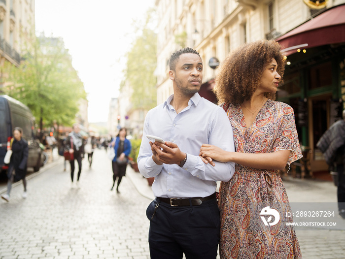 Couple looking away while standing on street in city