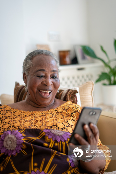 微笑的老年妇女在家用智能手机进行视频通话