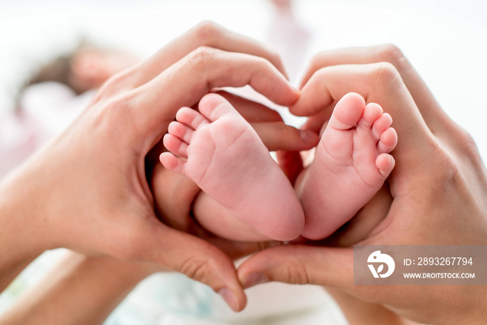 newborn baby feet on mom and dad hands, shape like a lovely heart. happy family concept
