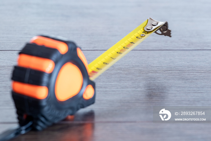 Tape measure on a wooden dark table, measuring tool