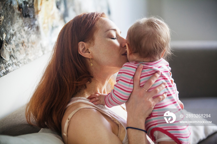 Mother kissing baby girl (6-11 months) on cheek