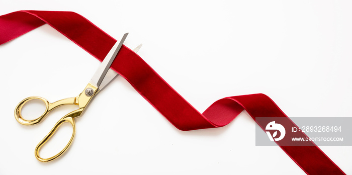 Grand opening, ribbon cut, overhead of gold scissors and red velvet ribbon isolated on white