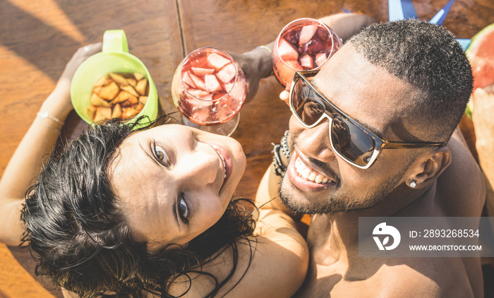 Fashion man and young woman having fun at cocktail bar drinking sangria - Happy multiracial couple a