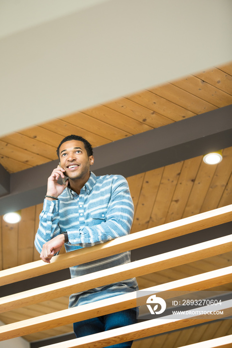 Young businessman on balcony making smartphone call