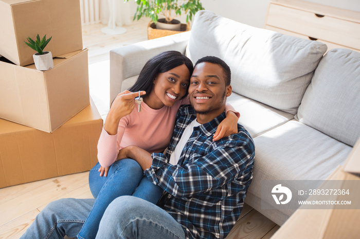 Black millennial lady with her husband hugging and holding house key in their new property