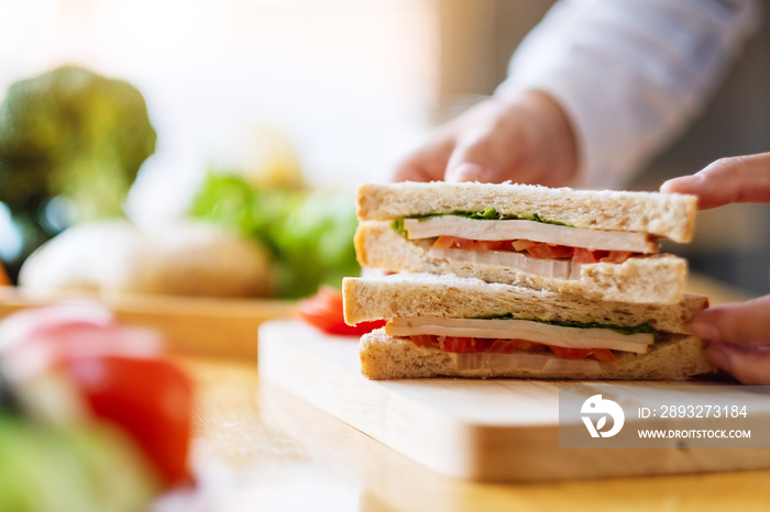 Closeup image of a female chef cooking and holding a piece of whole wheat sandwich in kitchen