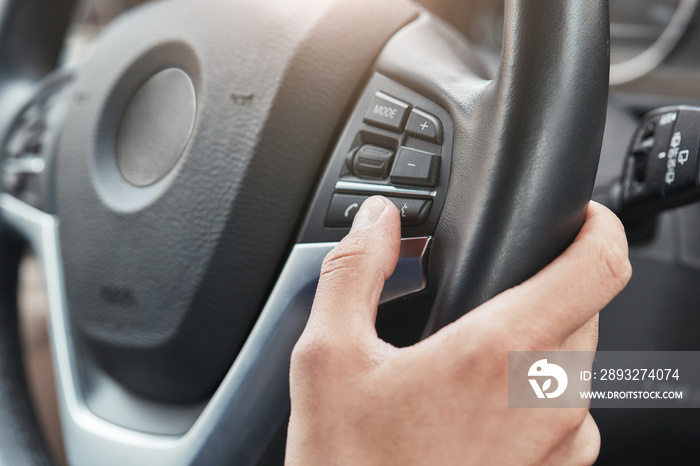 New car. Cropped image of a hand pushing control buttons on steering wheel in a modern car