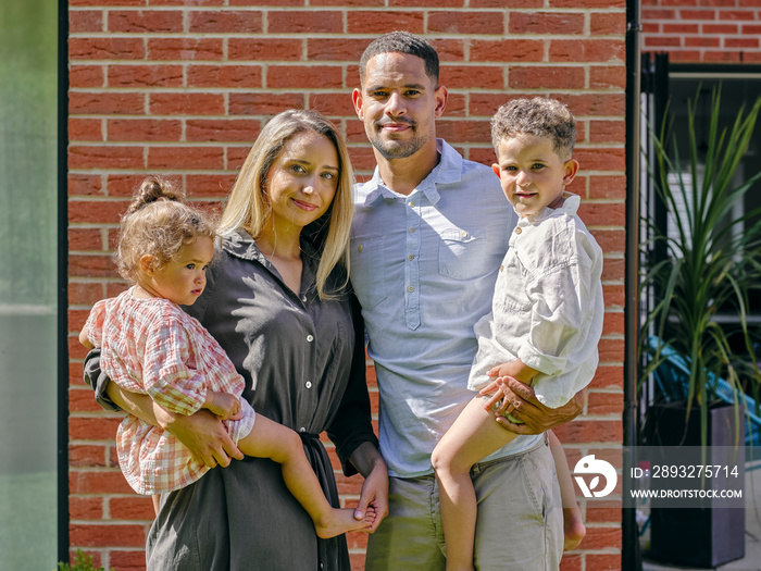 Portrait of parents with two children in front of house