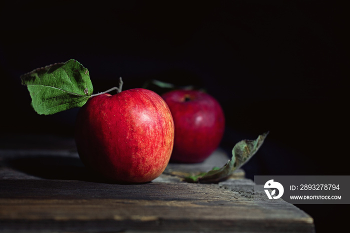 Two red apples on a wooden table. Low-key photography