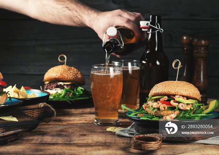 Different burgers with a light beer on a wooden table