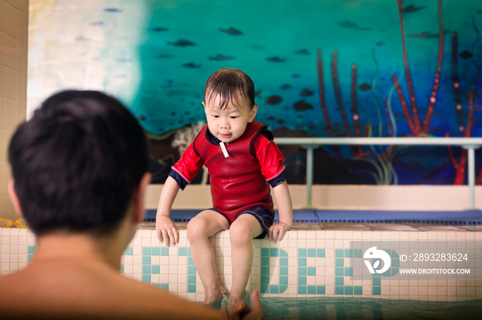 Father and son (2-3) in swimming pool