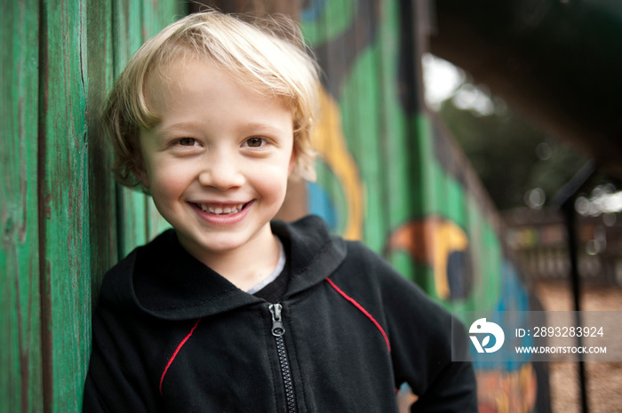 Portrait of boy leaning on wall at park