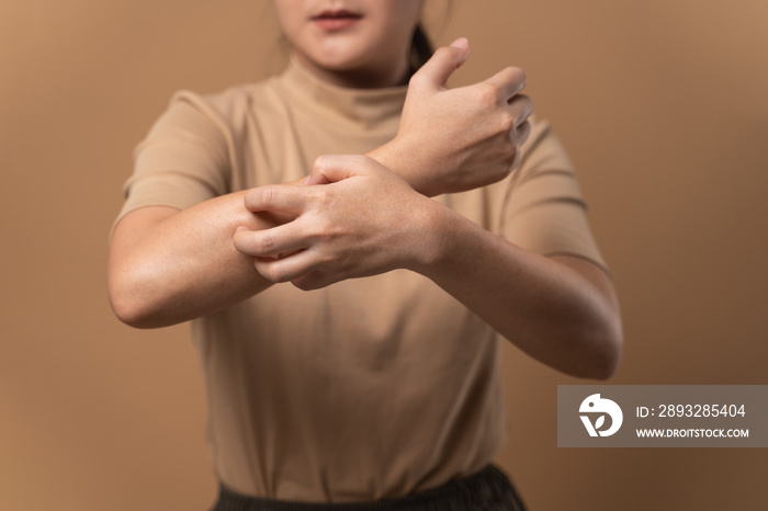 Asian woman was sick with irritate itching her skin standing isolated on beige background.