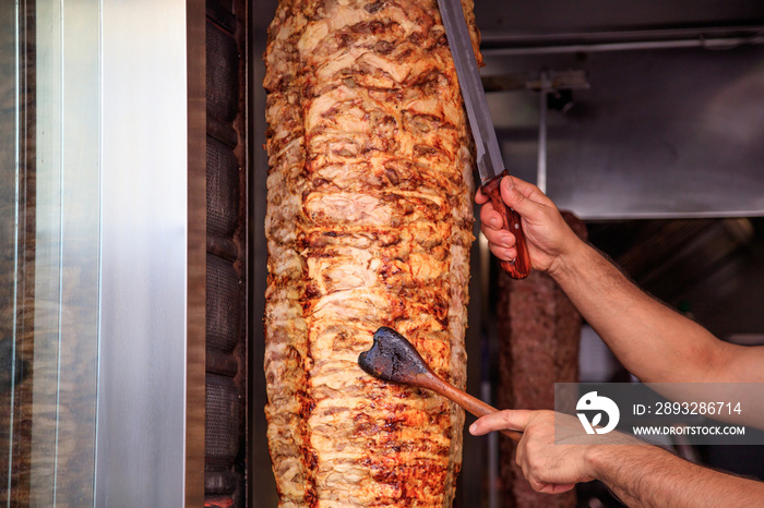 Gyros，doner。Mans hand hold a knife，cut slices（陀螺，烤面包。男人的手拿着刀，在切面包片）