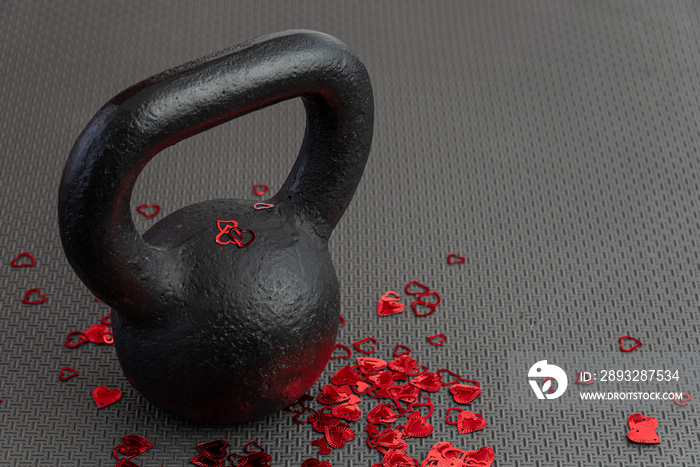 假日健身，黑色壶铃，红色心形五彩纸屑，在黑色健身房地板上