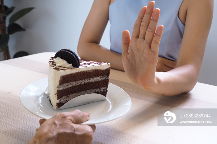 一名保健女孩用手推了一盘巧克力蛋糕。拒绝吃这种食物