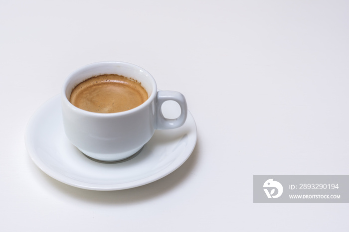 Mesa blanca con taza de café cremoso en el lado izquierdo