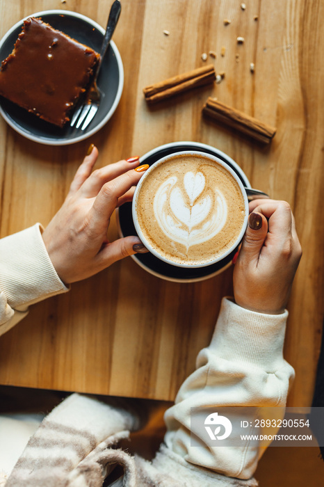 Women drinking Pumpkin spice latte at coffee shop; coffee and sweets on table. Seasonal coffe drinks