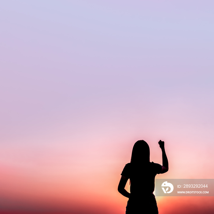 Woman raising her fist in the air in the morning.