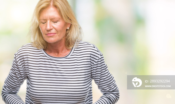 Middle age blonde woman over isolated background with hand on stomach because indigestion, painful i