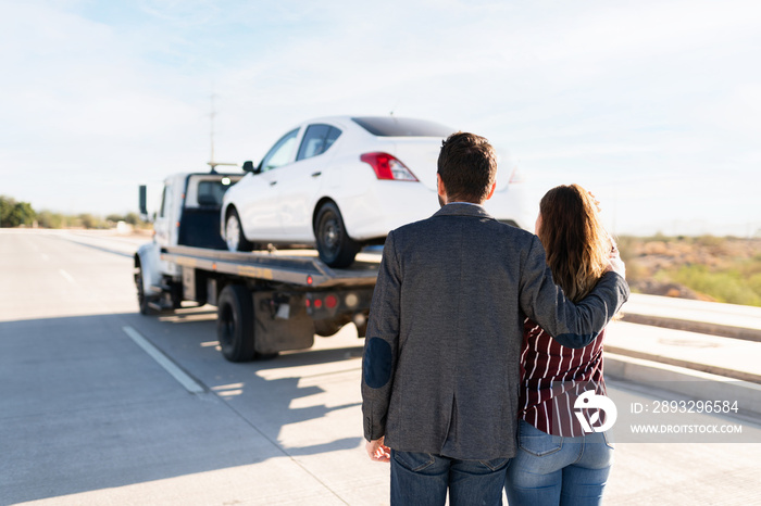 Man and young women hugging as they see their car being towed