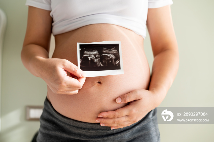 Pregnant woman feeling happy at home while taking care of her child. The young expecting mother hold