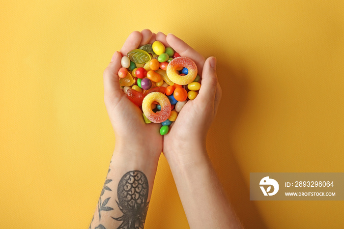 Woman holding colorful candies on yellow background