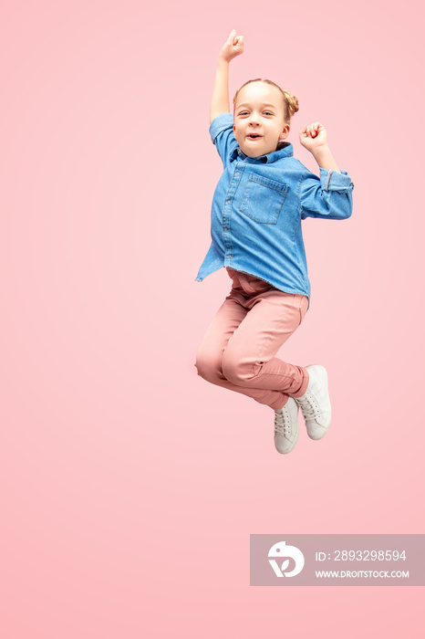 Young happy caucasian teen girl jumping in the air, isolated on pink studio background. Beautiful fe