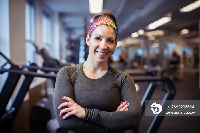 Portrait of smiling female athlete with arms crossed standing in health club