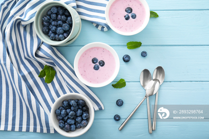 Bowls with tasty blueberry and yogurt on table