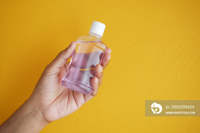 hand hold a mouthwash liquid container against blue background