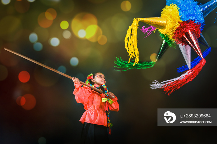 Mexican girl breaking a piñata in a Christmas inn with bright lights suna traditions of the December