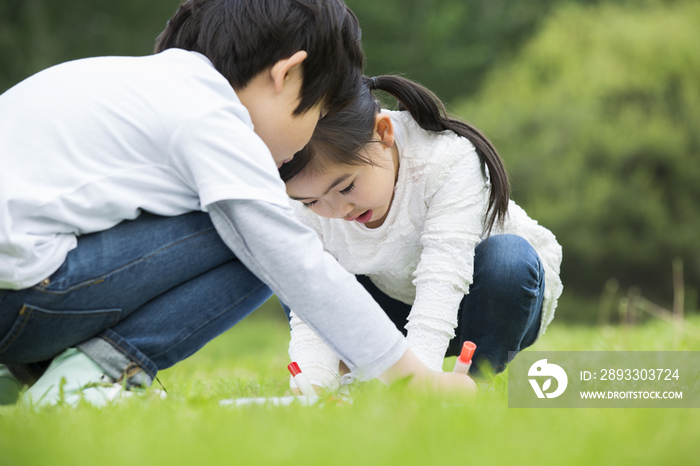 小男孩和小女孩在草地上画画