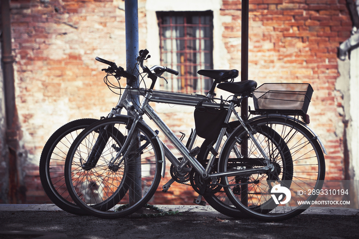 Two bikes resting against some poles in Venice, Italy