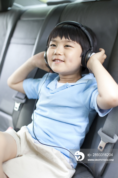 快乐的小男孩坐在车上听音乐