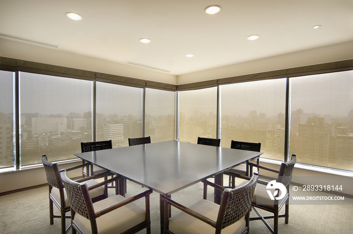 Table and chairs in conference room with the view of cityscape through window