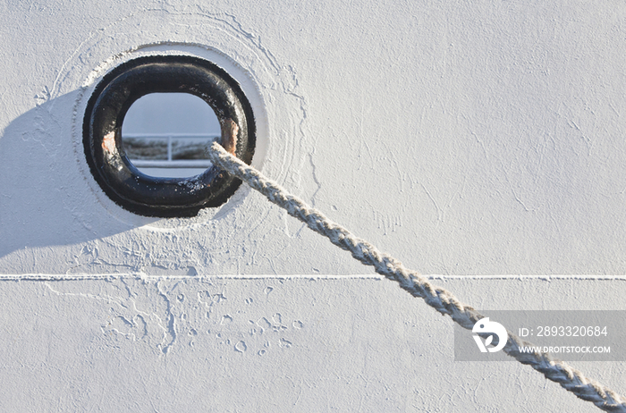 A hawsehole and hawser rope of a docked boat in a harbor