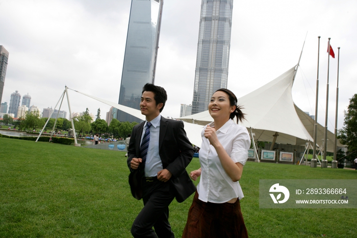 上海浦东金茂大厦前草坪上两位商务人士赛跑
