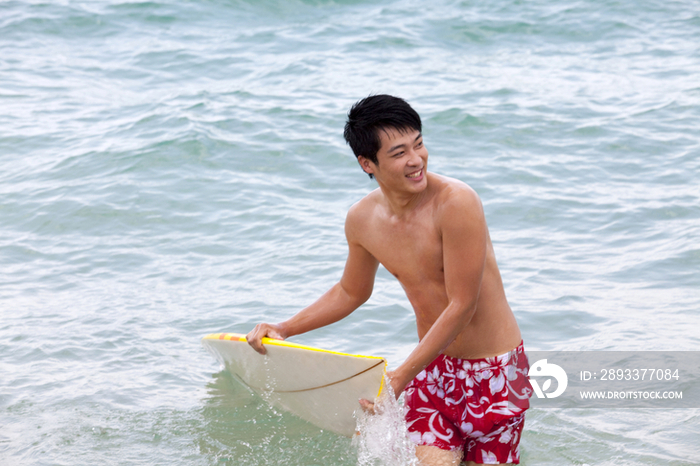 拿着冲浪板的男孩在海里