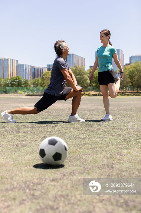 开心的中老年夫妇踢足球前做热身活动
