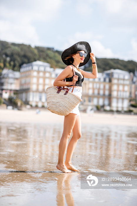 Portrait of a beautiful woman in hat walking on the beach with luxury houses on the background in Tr