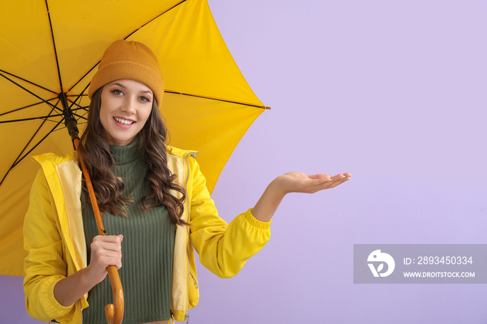 微笑的女人穿着雨衣，在彩色背景上打开雨伞