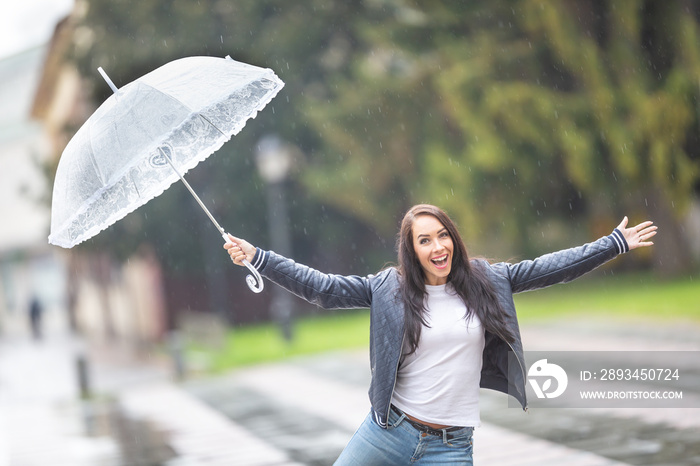 快乐的女孩在雨中唱歌，在城市公园里撑着伞远离她