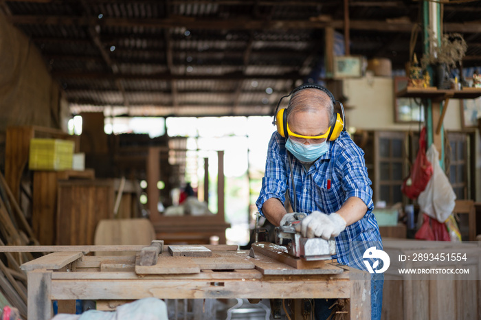 亚洲高级木匠戴卫生口罩用电刨在木板上调整表面保护
