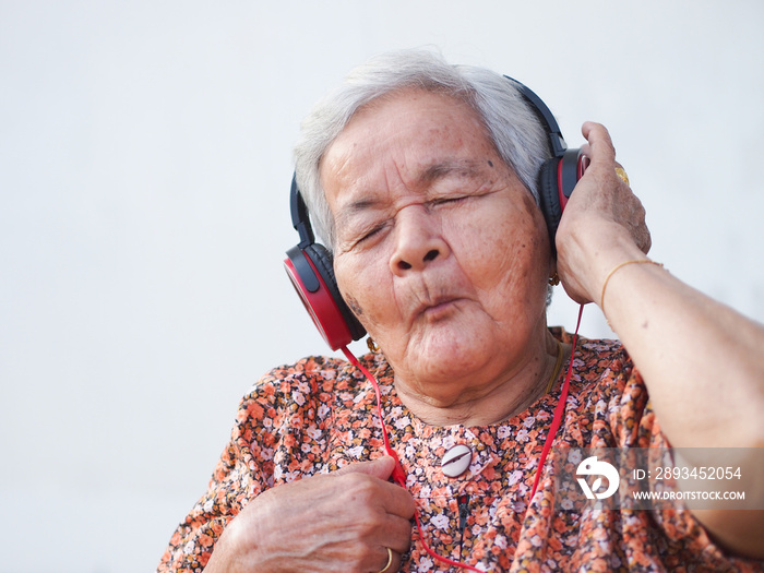 Funny old Asian woman listening music. Lifestyle senior elderly people concept.