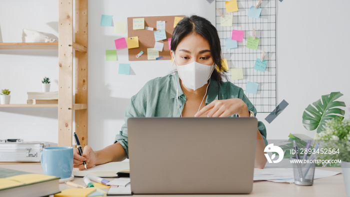 戴着医用口罩的亚洲女商人用笔记本电脑在视频通话中与同事谈论计划