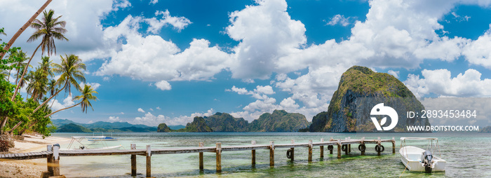 El Nido海岸线美丽的热带全景，码头码头、棕榈树、船、巨大的石灰岩