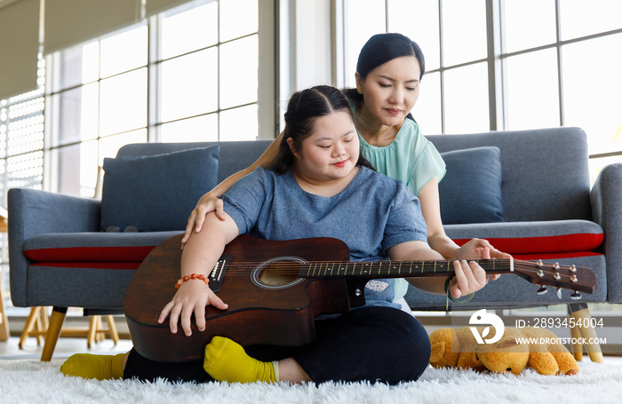 Asian lovely mother helping young chubby down syndrome autistic autism little daughter holding playi