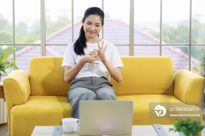 Young and beautiful Asain woman using notebook computer and demonstrat and communicate with hand sig